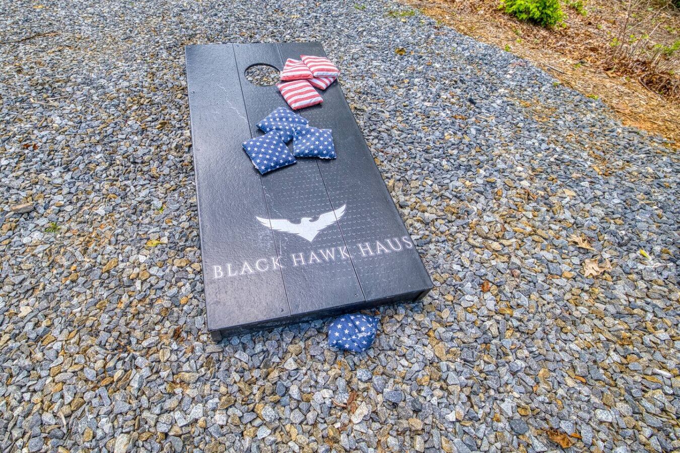 A wooden board with 'BLACK HAWK HOUSE' text and a bird logo, placed on a gravel surface.