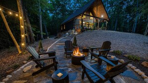 Eine Blockhütte mit Feuerstelle und Sitzgelegenheit im Freien.