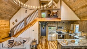 Ein geräumiger Innenraum im Loft-Stil mit Küche, Essbereich und einer Treppe, die zu einer erhöhten Ebene führt.