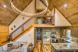Ein geräumiger Innenraum im Loft-Stil mit Küche, Essbereich und einer Treppe, die zu einer erhöhten Ebene führt.