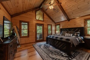A wooden cabin bedroom with a bed, dresser, and a ceiling fan. - Mountain Memories:HotTub, GameRoom-KingSuites (Blue Ridge)