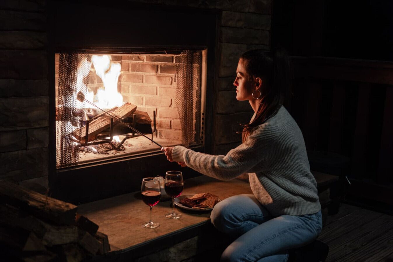 Iemand zit bij een open haard, voor een tafel, en houdt een lucifers aan.