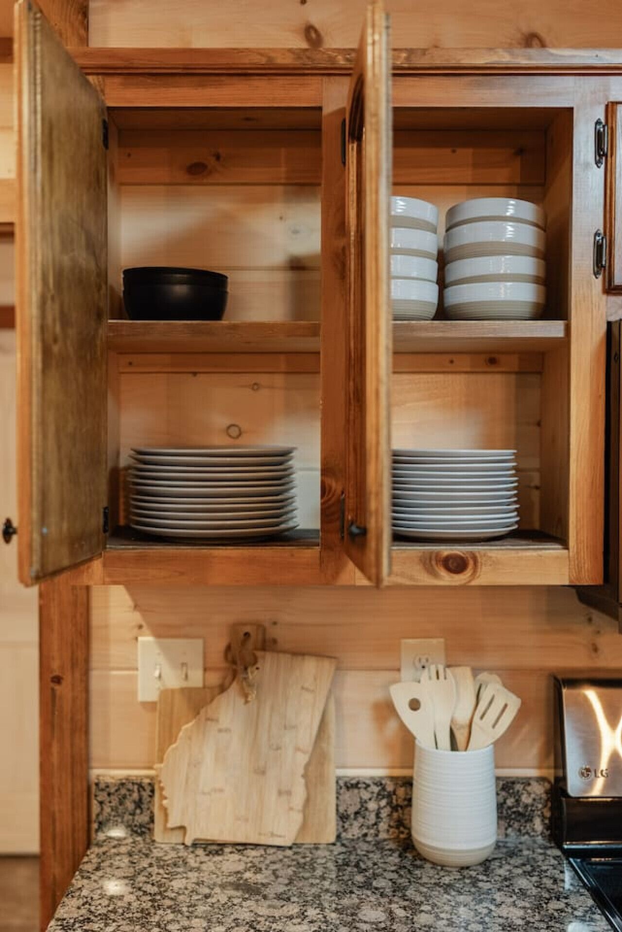 A wooden kitchen cabinet with plates and bowls.