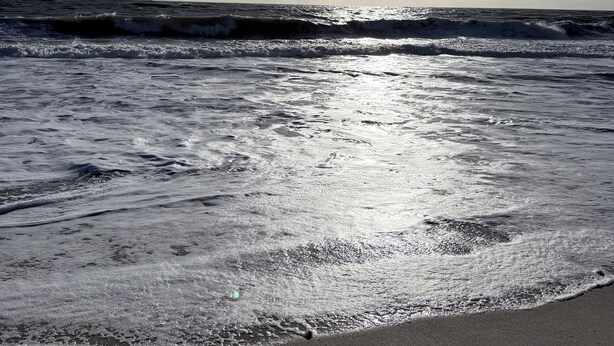 Uma praia com ondas e céu claro.