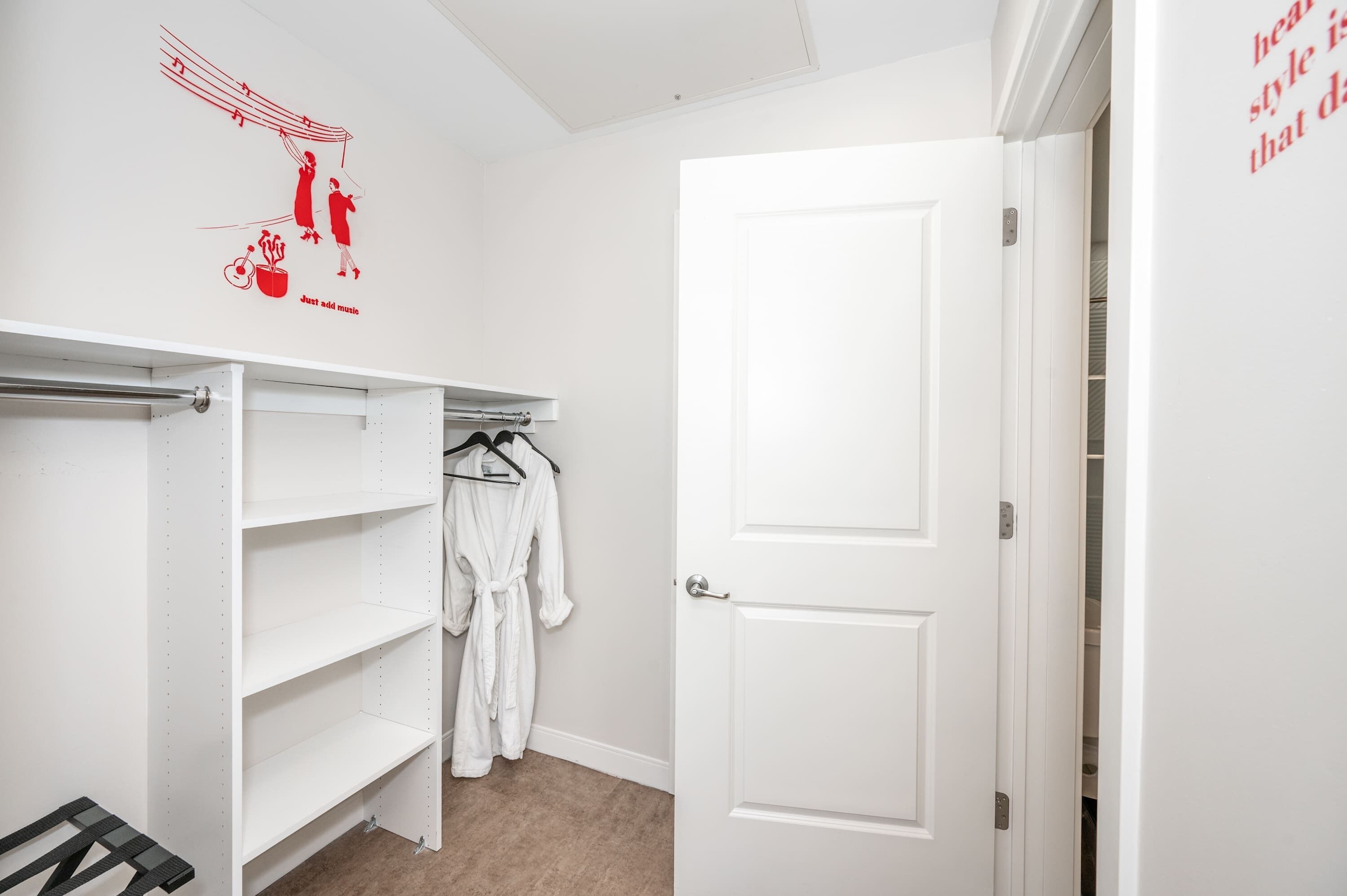 A white closet with shelves, a robe hanging, and a door with a white frame.