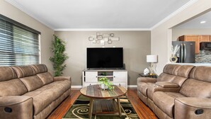 A living room with two leather sofas, a wooden coffee table, a flat-screen TV, and a decorative wall piece. - 324 Beautiful Residence in Mebane NC. (Mebane)