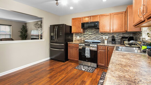 A modern kitchen with wooden cabinets, stainless steel appliances, a granite countertop, and a backsplash. - 324 Beautiful Residence in Mebane NC. (Mebane)