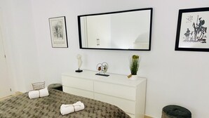 Un dormitorio con cama, cómoda, espejo y decoración en la pared.