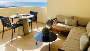 Un balcón con una mesa, sillas, un sofá y una planta en maceta.