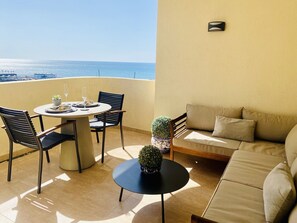 A balcony with a table, chairs, a sofa, and a potted plant.