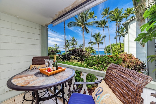 A balcony with a table, chairs, and a bottle of champagne. - Ocean-view Condo – Private Lanai - In Kona Town (Kailua-Kona)