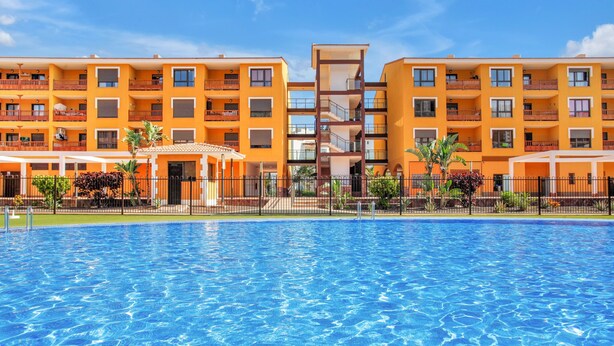 A hotel with a swimming pool, multiple balconies, and a central tower.
