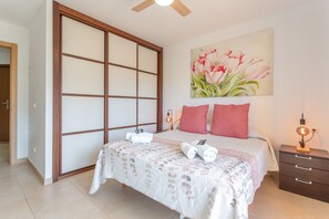 A bedroom with a bed, a nightstand, a painting, and a sliding door. - Ocean Eyes! with Terrace and Communal Pool (Palm-Mar)