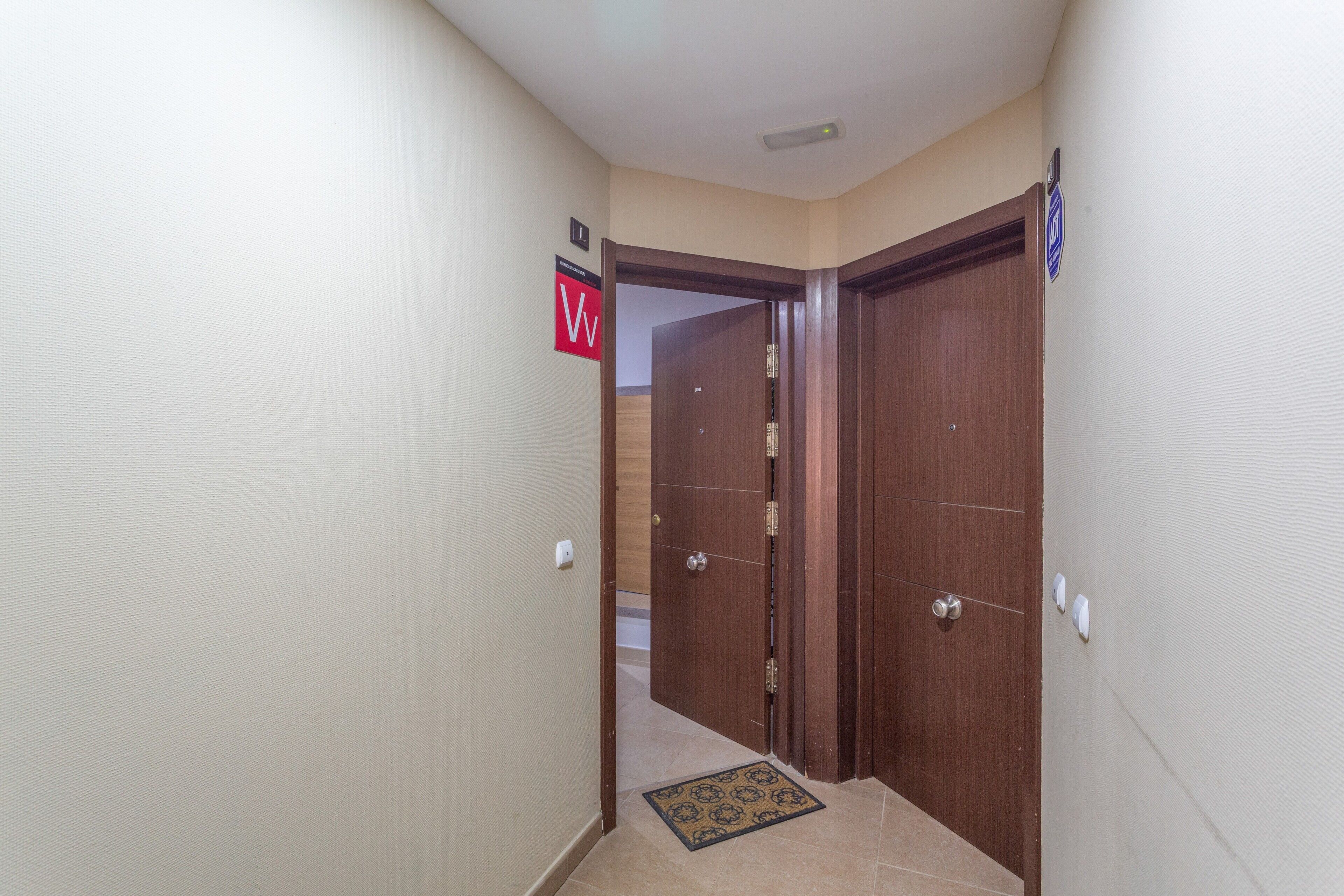 Un pasillo con una puerta de madera, un felpudo y un cartel que indica el baño de mujeres.