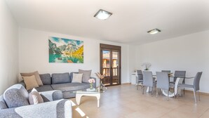 A modern living room with a sofa, coffee table, and dining area with chairs.