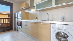 A modern kitchen with a built-in washing machine, a stainless steel refrigerator, and wooden cabinets.