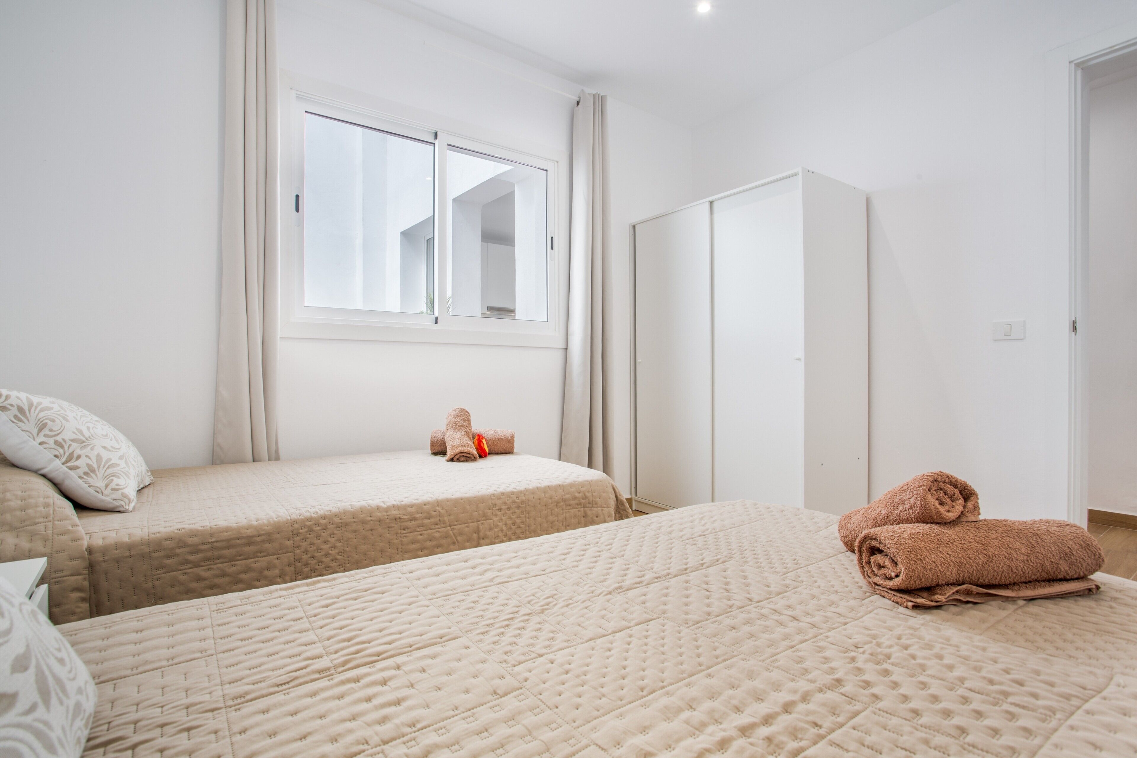 Een slaapkamer met twee bedden, een kledingkast en een raam.