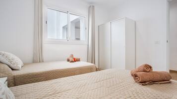 Een slaapkamer met twee bedden, een kledingkast en een raam.