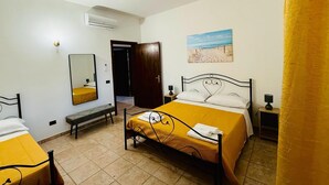 A hotel room with a bed, a bench, a desk, a chair, a mirror, a painting, and an air conditioning unit. - Villa Gioia (Puglia)