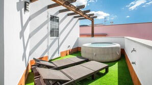 Une terrasse sur le toit dotée d’un jacuzzi, de chaises longues et d’une pergola.