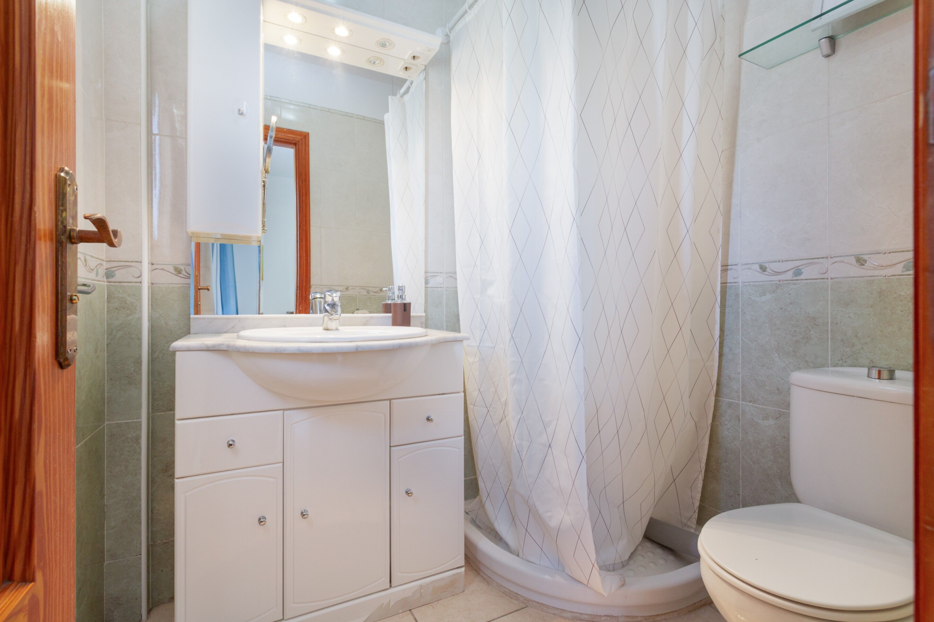 Un baño con inodoro, lavamanos y cortina de ducha.