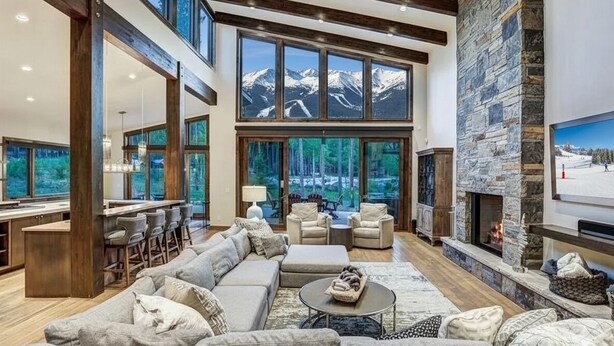 A spacious living area with a large couch, a fireplace, and a view of mountains through large windows. - ✨ Soltierra • 🏔️ Breck Peak 8 • 🎿 Ski-In • 💦 10-Person Spa • 🛏️ 13 Beds (Breckenridge)