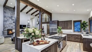 A modern kitchen with a central island, built-in appliances, and a stone accent wall. - ✨ Soltierra • 🏔️ Breck Peak 8 • 🎿 Ski-In • 💦 10-Person Spa • 🛏️ 13 Beds (Breckenridge)
