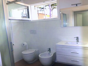 Un baño con inodoro, bidé y lavabo con espejo encima.