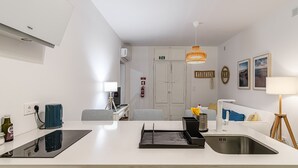 Una cucina moderna con un piano di lavoro bianco, un forno integrato, un lavello e un'area pranzo con sedie a righe.