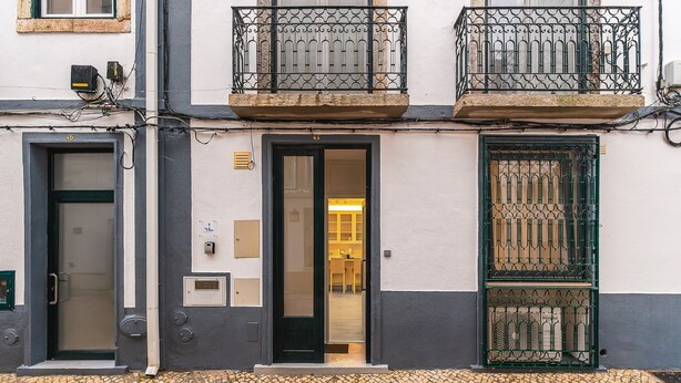 Un edificio con ingresso al piano terra, un balcone con ringhiera in ferro battuto e una porta con finestra.