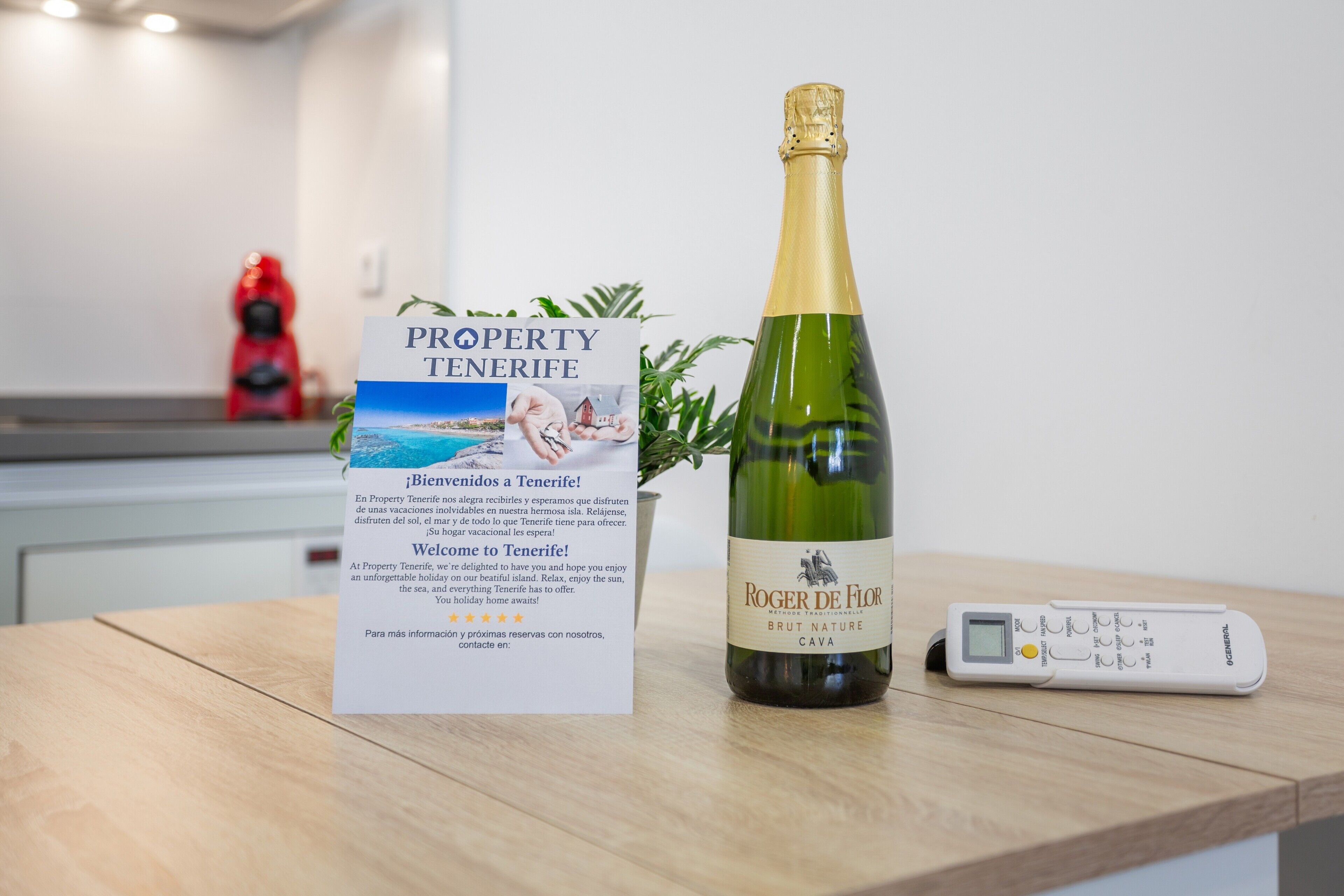 Een fles Roger de Flor Brut Nature Cava, een brochure voor Property Tenerife en een digitale thermometer op een houten oppervlak.
