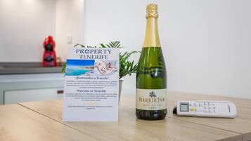 Een fles Roger de Flor Brut Nature Cava, een brochure voor Property Tenerife en een digitale thermometer op een houten oppervlak.