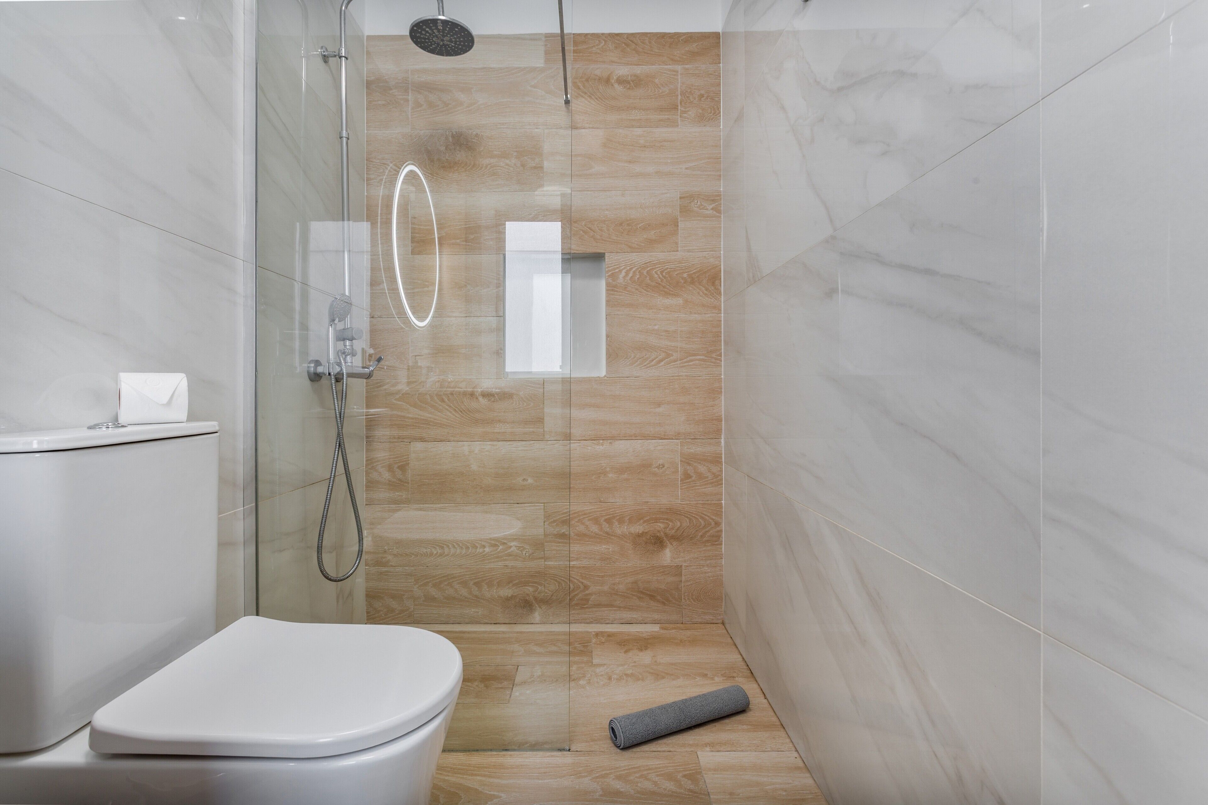 Une salle de bain moderne avec une douche à parois de verre, des toilettes et un plancher en bois.