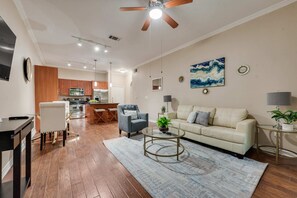 A modern living room with a sofa, coffee table, and a dining area with a table and chairs. - GV001 |Spacious 1BD Apt| D/town Grapevine (Grapevine)