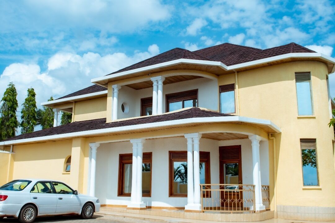 A two-story house with a balcony, columns, and a car parked in front.