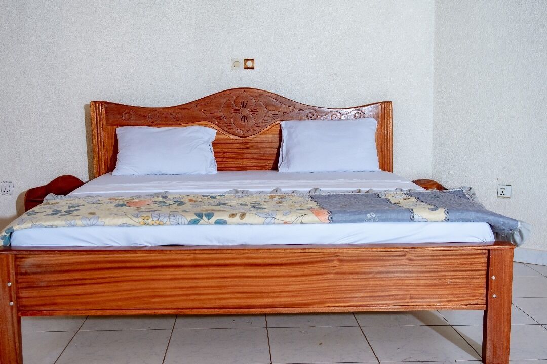 A wooden bed with a floral-patterned bedspread and two white pillows.