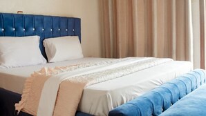 Una cama bien hecha con un cabecero azul y ropa de cama blanca.