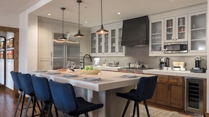 A modern kitchen with a central island, bar stools, stainless steel appliances, and pendant lighting. - Slopeside Residence at One Steamboat Place | Longs Peak #609 (Steamboat Springs)