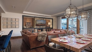 A modern living room with a leather sofa, dining table set for four, and a fireplace. - Slopeside Residence at One Steamboat Place | Longs Peak #609 (Steamboat Springs)