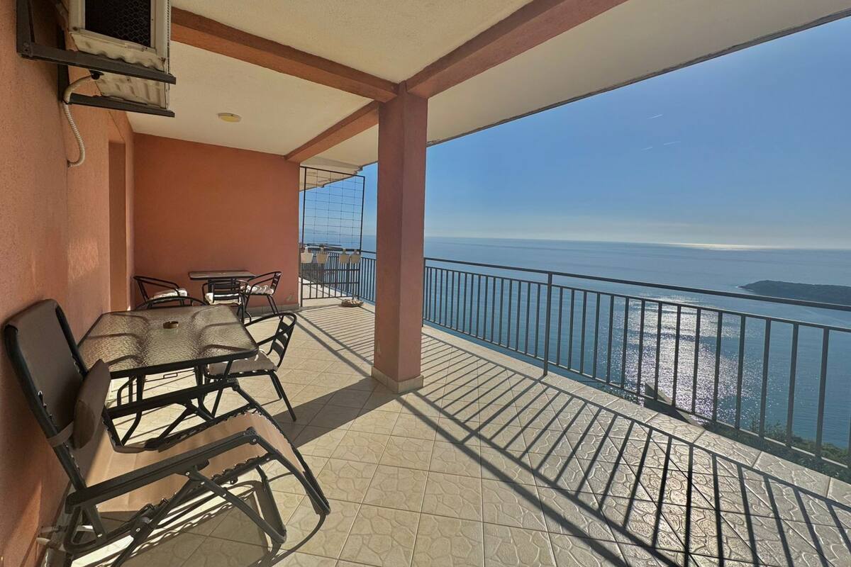 Un balcon avec une table et des chaises, une vue sur la mer et un sol carrelé.