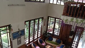 A spacious living area with large windows, wicker furniture, and a foosball table. - Ronglyang homestay  (Gangtok)