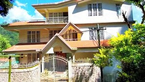 A two-story house with a gated entrance, a balcony on the upper floor, and a stone wall surrounding the property. - Ronglyang homestay  (Gangtok)