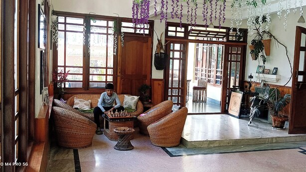 A traditional room with wicker furniture, a chessboard, and a view of the street through large windows. - Ronglyang homestay  (Gangtok)