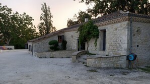 A stone building with a tiled roof, a small garden area, and a gravel path.
