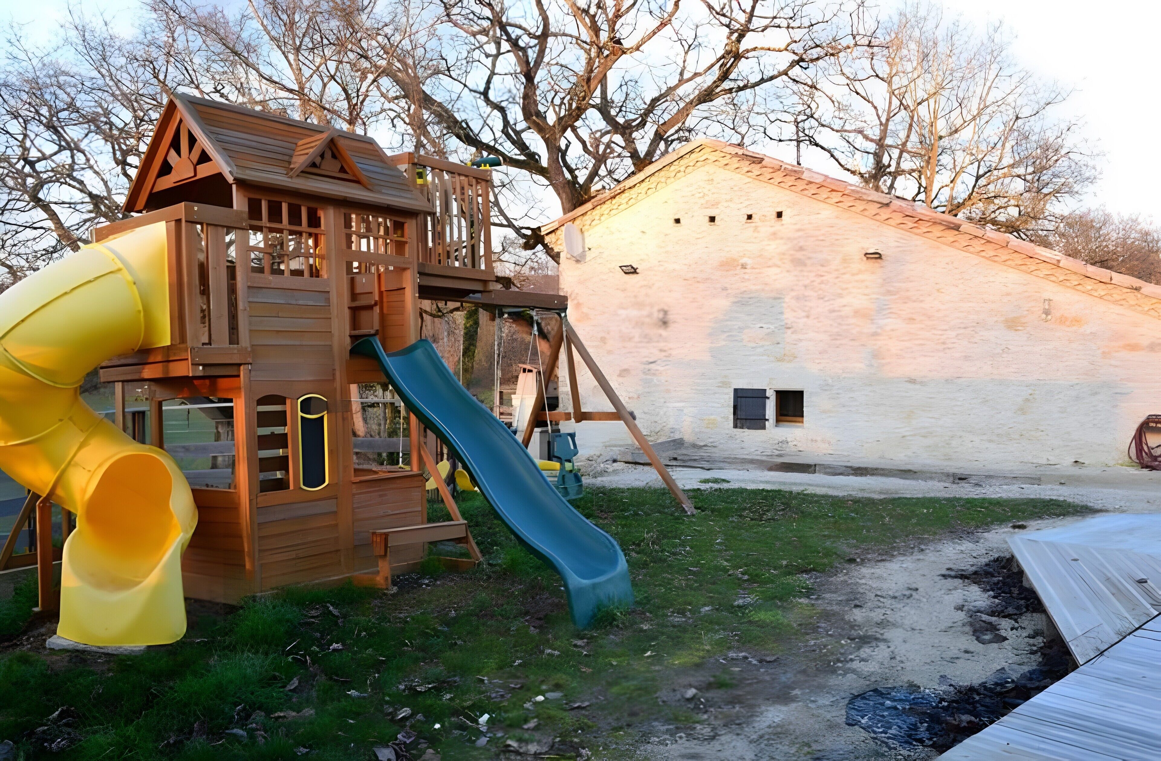 Ein Spielplatz mit Rutsche und Holzspielhaus.