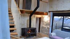 A stone-walled room with a fireplace, a staircase, and a sofa.