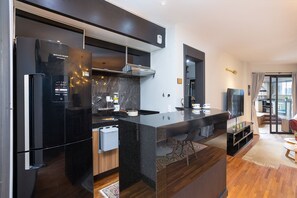 Une cuisine moderne avec un réfrigérateur noir, une cuisinière encastrée et un grand îlot central.