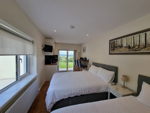 A bedroom with two beds, a TV, a desk, and a painting. - Misty Bay (Dawros)
