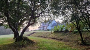 A house with a sloped roof, surrounded by trees and a grassy area. - Misty Bay (Dawros)
