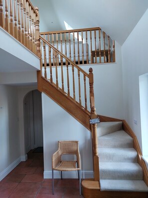A wooden staircase with a handrail and a sign instructing to remove shoes before going upstairs. - Misty Bay (Dawros)